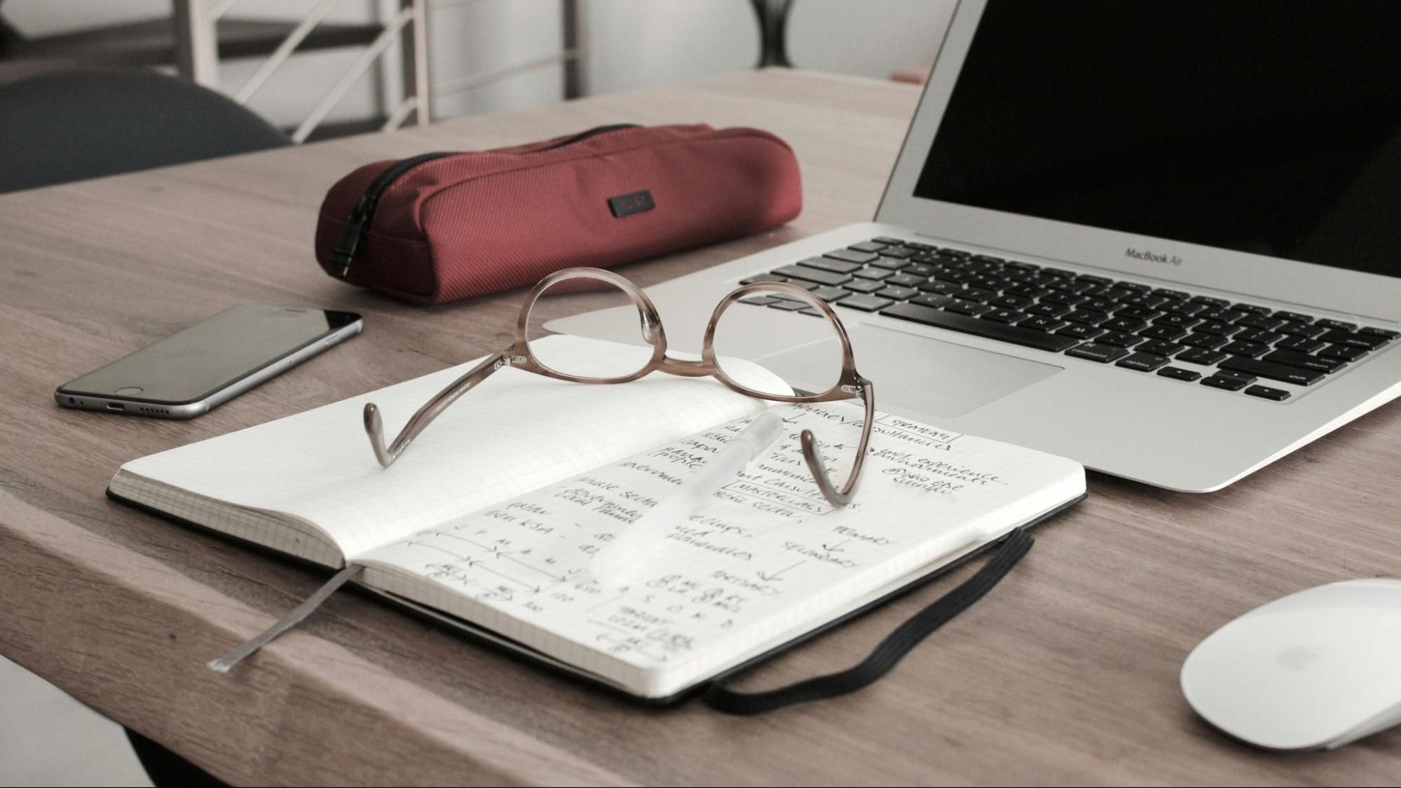 A journal and laptop laid out for tracking expenses and managing a budget.