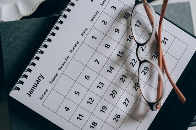 A monthly calendar page with reading glasses resting on it
