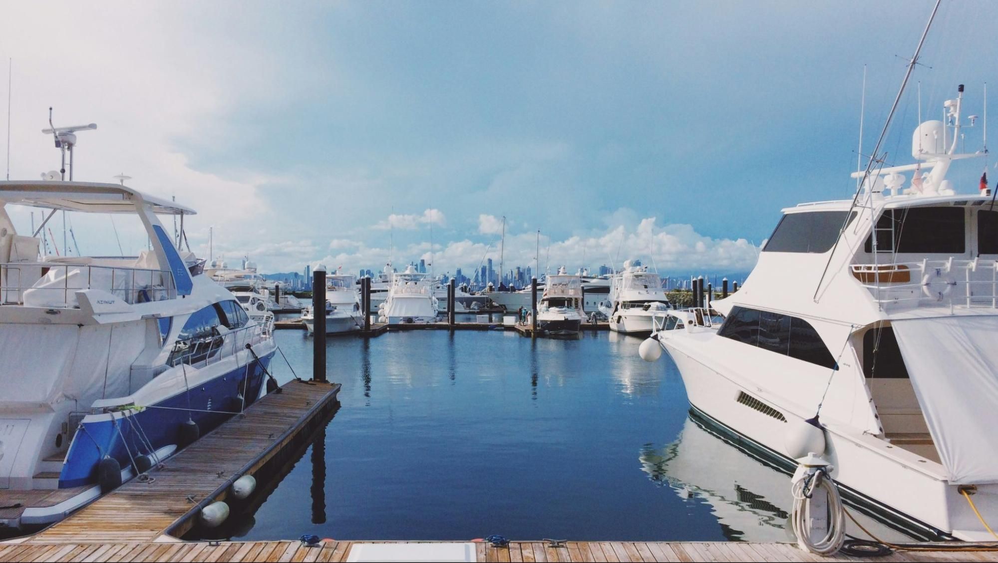 Several yachts docked side by side at a marina in a calm bay.