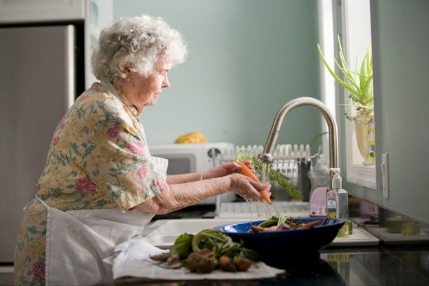 Senior woman washing vegetables in the kitchen sink