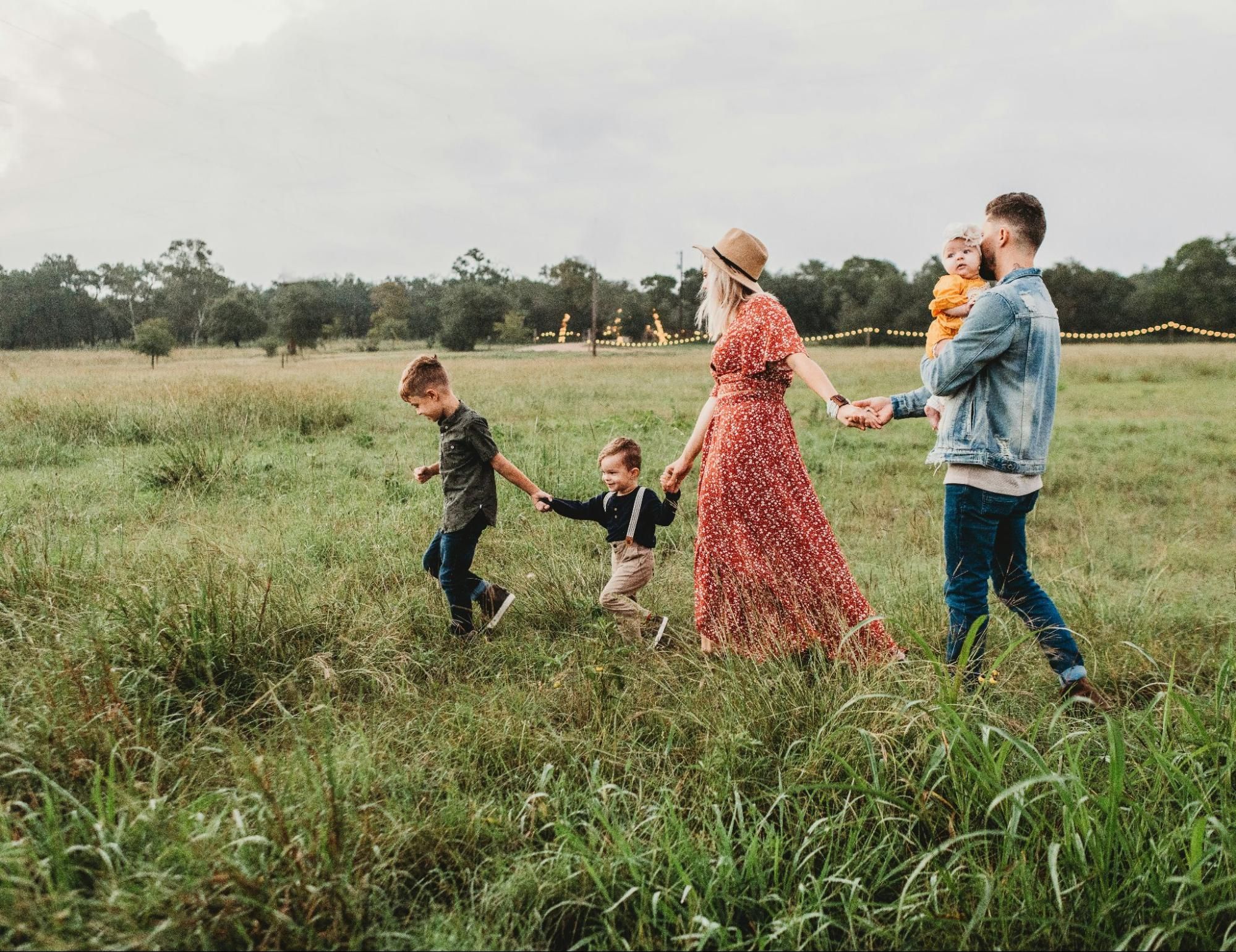 A family holding hands while talking together outdoors on green grass.