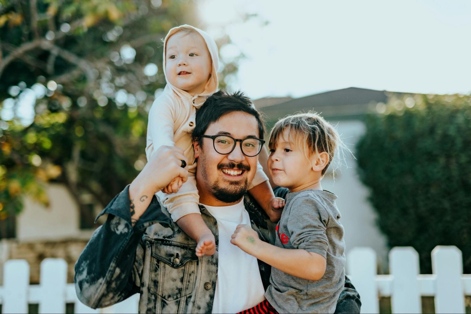A father holding his two young children.