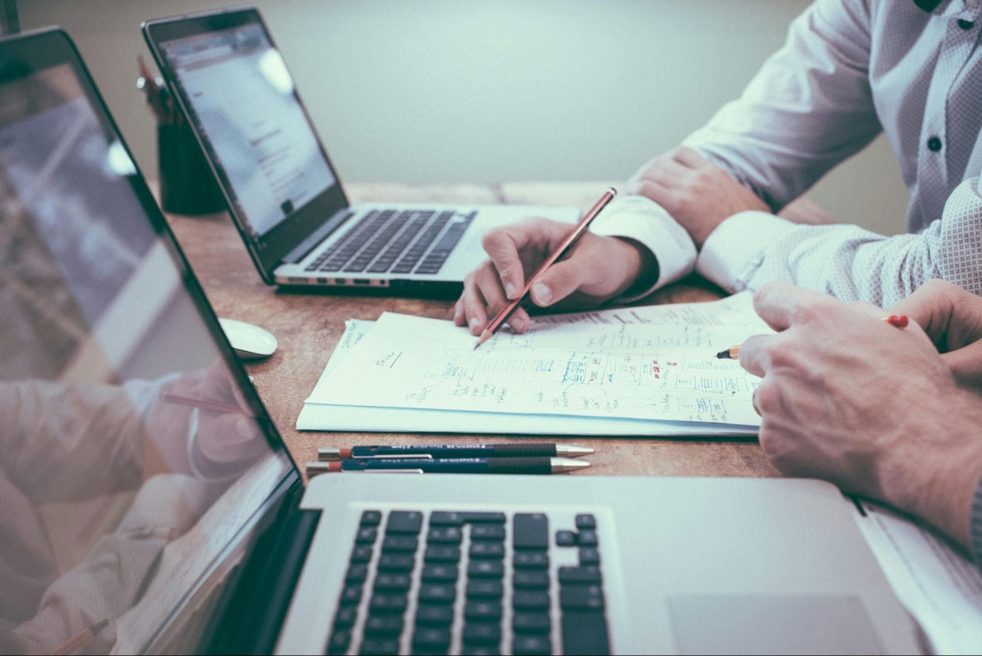 A financial advisor and client discussing financial strategy with documents and laptops.