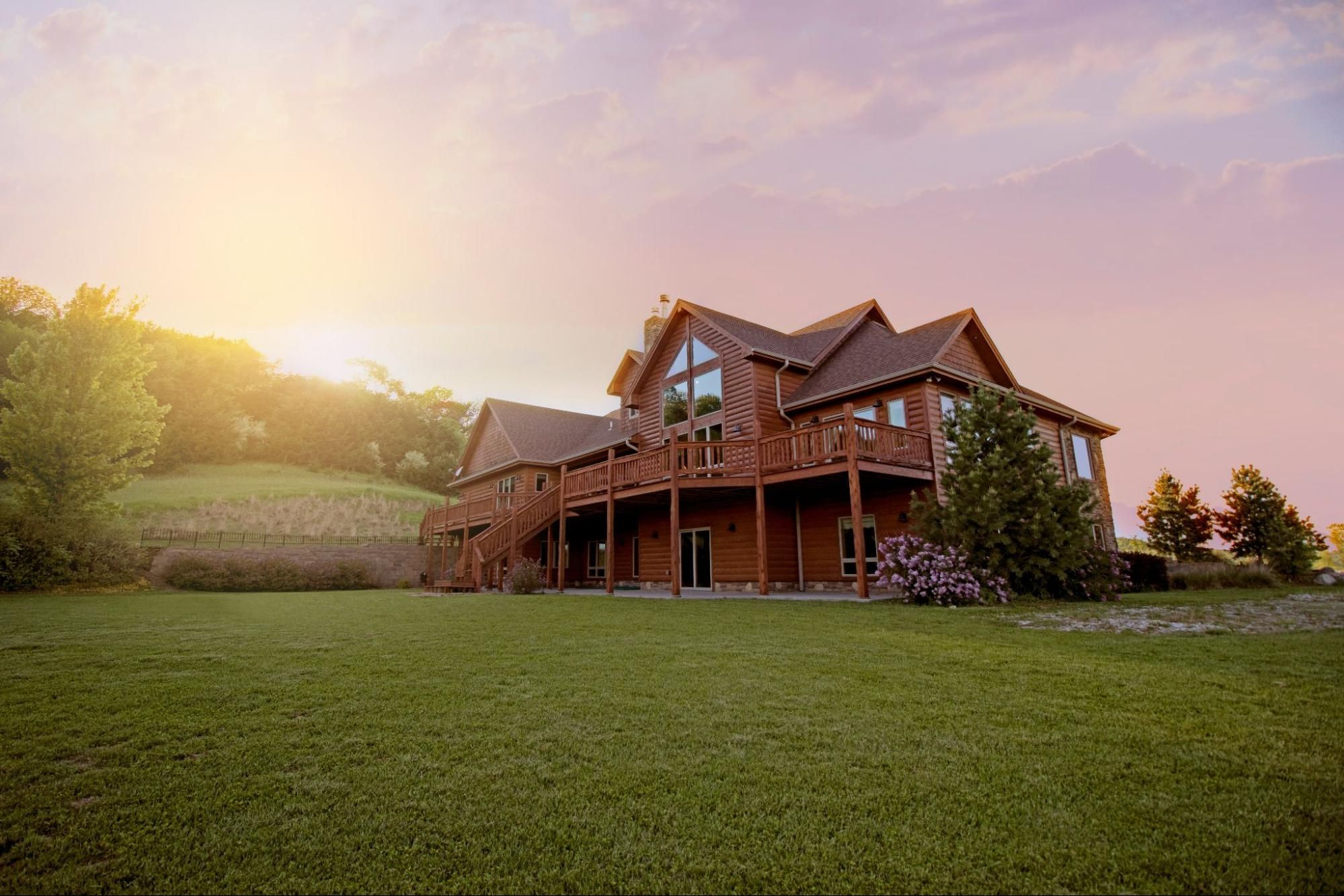 Spacious log house in a grassy field.