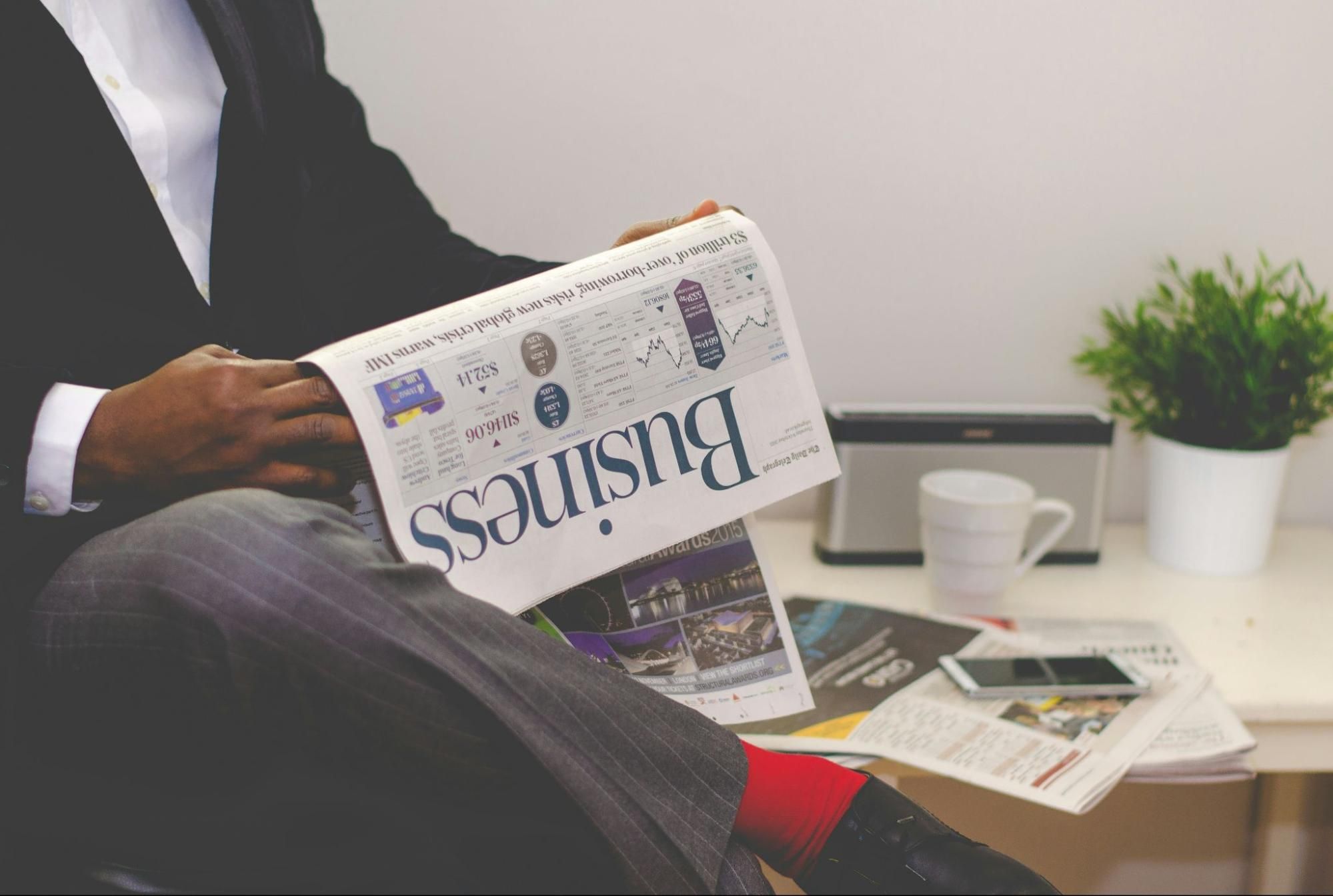 Businessman in formal attire reading a newspaper with a business headline