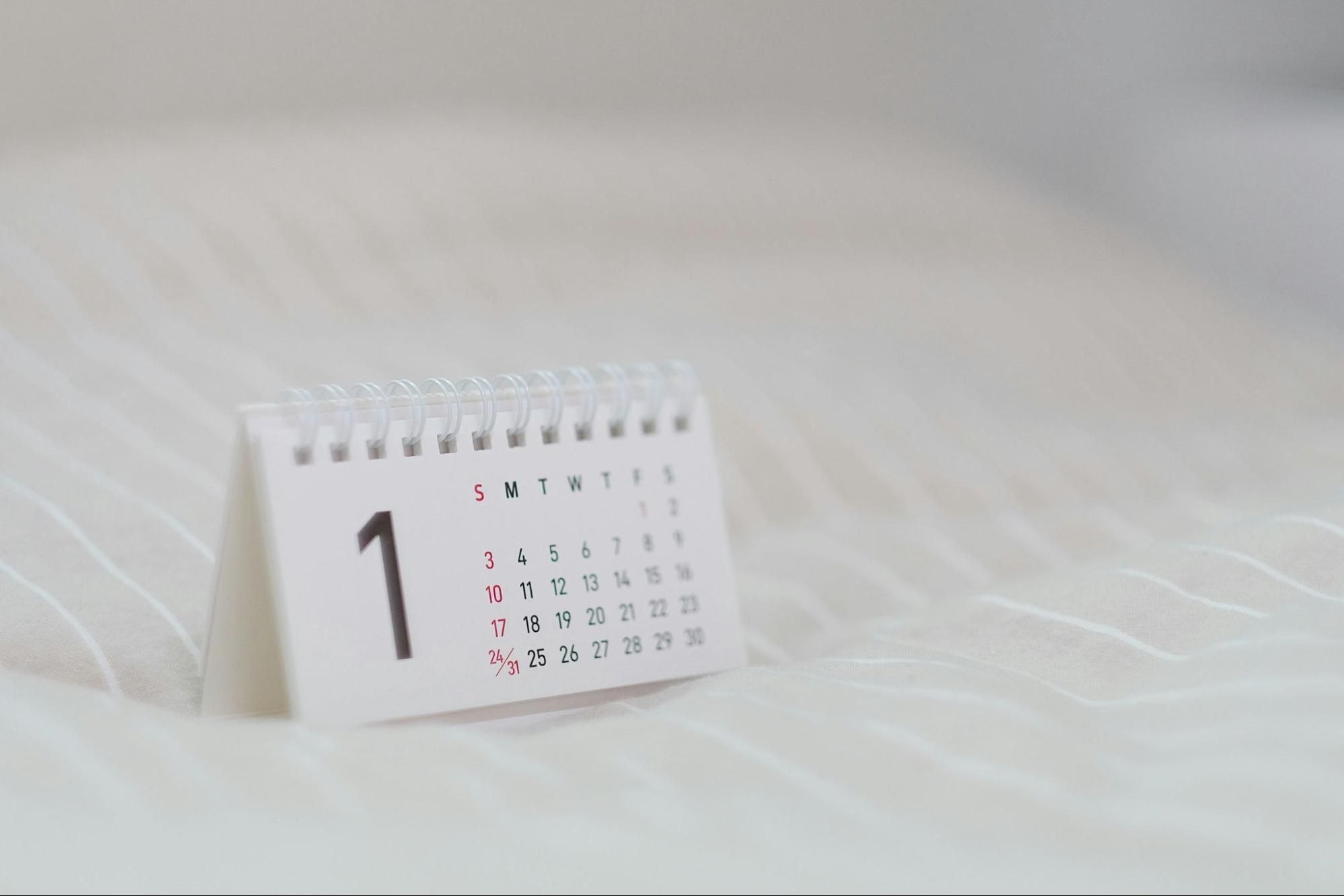 A compact stand calendar on fabric, showing all dates of a full month.